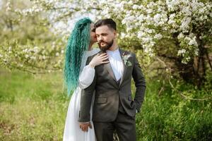 uma barbudo noivo e uma menina com verde cabelo estão caminhando foto