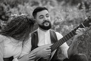 uma barbudo noivo tocam uma amarrado instrumento e uma menina senta dentro uma Primavera Prado foto