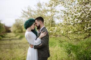 uma barbudo noivo e uma menina com verde cabelo estão caminhando foto