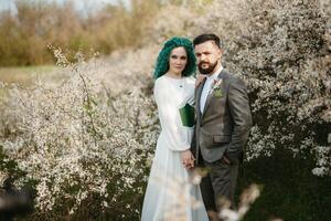 uma barbudo noivo tocam e uma menina com verde cabelo contra a fundo do florescendo Primavera foto