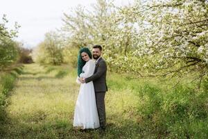 uma barbudo noivo e uma menina com verde cabelo estão caminhando foto