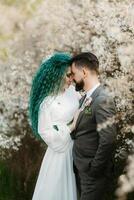 uma barbudo noivo tocam e uma menina com verde cabelo contra a fundo do florescendo Primavera foto