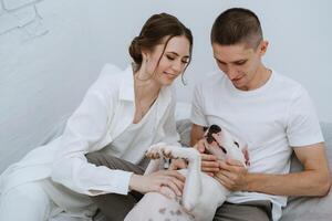 jovem casal cara e menina dentro uma brilhante quarto jogando com animal foto