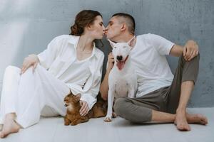 jovem casal cara e menina dentro uma brilhante quarto jogando com animais de estimação foto