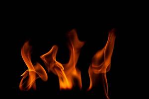 quente chamas em uma Preto fundo. lindo chama do fogo dentro a escuro. abstrato do queimando chamas e fumaça. foto