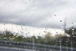 pingos de chuva em uma janela com uma borrado paisagem urbana dentro a fundo. foto