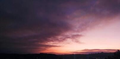 panorama épico Sombrio azul céu às pôr do sol com laranja nuvens. foto