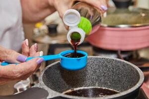 chef mãos derramando xarope para dentro tigela com mistura para casa cozinhando foto