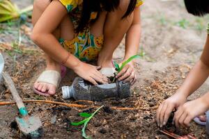 pequeno menina plantio plantas dentro panelas a partir de reciclado água garrafas dentro a quintal. reciclar água garrafa Panela, jardinagem Atividades para crianças. reciclando do plástico desperdício foto