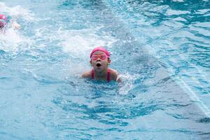 bonita pequeno menina natação e jogando dentro água. crianças dentro natação piscina tendo Diversão durante família verão período de férias. foto