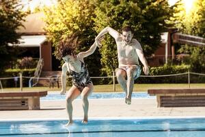 jovem casal do amantes pulando dentro a natação piscina foto