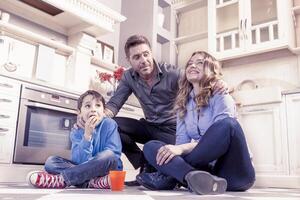 família relaxante em chão dentro a cozinha foto