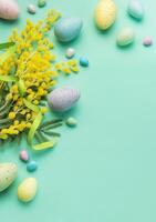 festivo Páscoa decoração com colorida ovos e mimosa flores em uma pastel verde fundo foto