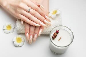 mão do uma jovem mulher com branco pérola manicure foto