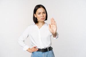 retrato do jovem mulher estendendo 1 mão, Pare tabu sinal, rejeitando, declinante algo, em pé sobre branco fundo foto