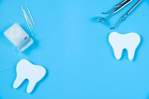 feliz dentista dia. papel cortar brincar do dente e dental ferramenta em azul fundo. dental Cuidado conceito. foto