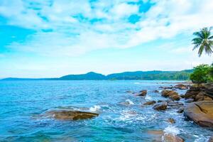 marinha do uma tropical de praia com Palma árvores ,paisagem do azul céu, montanha e nuvens foto