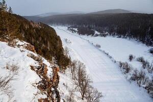 inverno Visão do a coberto de neve natureza dentro a montanhas. ural montanhas, Rússia. Rocha parede em uma congeladas rio. sulista Urais, Chelyabinsk região foto
