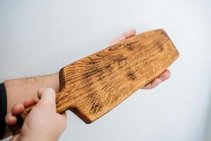 corte borda para cozinhando dentro a cozinha. uma de madeira borda dentro a mãos do uma cara. utensílios de cozinha. feito à mão carpinteiro item. foto