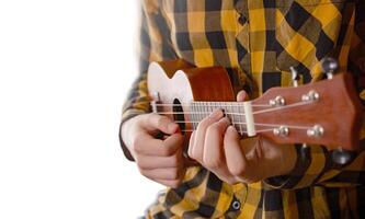 uma jovem homem jogando ukulele. fechar acima Visão foto