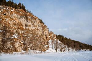 inverno Visão do a coberto de neve natureza dentro a montanhas. ural montanhas, Rússia. Rocha parede em uma congeladas rio. sulista Urais, Chelyabinsk região foto