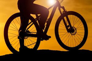 silhueta do ciclistas às bicicleta às pôr do sol. veículo fechar-se. rio fundo. foto