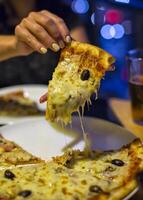 uma fatia do pizza dentro dele mão uma restaurante lindo fundo foto
