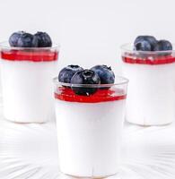 vidro copo do iogurte com amoras em branco mesa foto