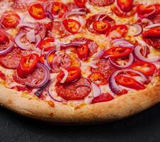 saboroso calabresa pizza com vermelho Pimenta Pimenta e cebola foto