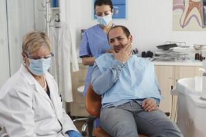 especialista dentista equipe explicando cárie infecção para doente paciente com dor de dente discutindo médico perícia durante estomatológico consulta dentro dental escritório. conceito do remédio serviço foto