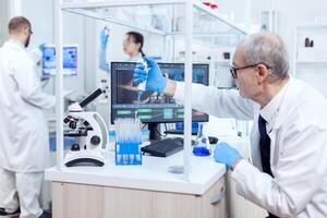 cuidados de saúde especialista dentro química laboratório fazendo científico pesquisa com conta-gotas distribuidor. Senior profissional químico usando pipeta com azul solução para microbiologia testes. foto