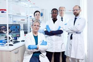 cuidados de saúde investigador às local de trabalho em pé juntos com braços cruzado. africano cuidados de saúde cientista dentro bioquímica laboratório vestindo estéril equipamento. foto