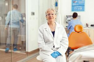 retrato do especialista médico trabalhando dentro estomatológico escritório quarto preparando para odontologia cirurgia durante doente homem paciente ortodôntico consulta. médico enfermeira analisando dente raio X foto