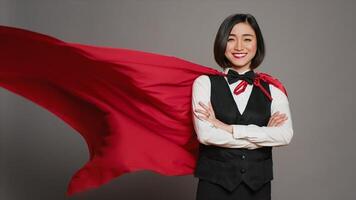 hotel administrador vestindo uma vermelho herói capa em Câmera, sentindo-me Forte e poderoso para Socorro clientes. ásia recepcionista posando com confiança usando uma Super heroi capa sobre cinzento fundo. Câmera uma. foto