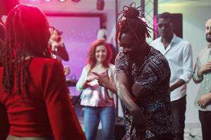 africano americano casal mostrando movimentos em lotado pista de dança dentro Boate. homem e mulher despreocupado dançarinos improvisando dança batalha para jovem pessoas às discoteca festa dentro clube foto