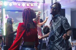 relaxado africano americano homem e mulher dançarinos festa em Boate pista de dança. jovem namorado e namorada casal dançando junto, tendo Diversão e a comemorar dentro clube foto