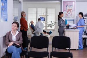 pacientes dentro estomatologia recepção esperando dentro linha levando o preenchimento forma, médico examinando Senior homem discutindo tee assistência médica. estomatologia corredor com pessoas esperando consulta. foto