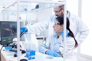 determinado profissional cientistas vestindo uniforme trabalhando com assistente às ambiente de trabalho. equipe do pesquisadores fazendo farmacologia Engenharia dentro estéril laboratório para cuidados de saúde indústria. foto