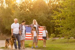 grande família estão caminhando caminhando americano bandeiras. frente visualizar, americano patriotas em a parque Prado. foto
