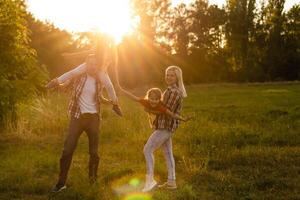 feliz família mãe pai e criança filha em natureza em pôr do sol foto