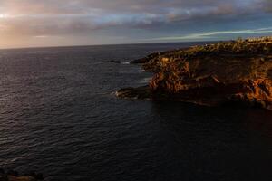 panorâmico Visão do a iluminado las Américas às noite contra a colorida pôr do sol céu com luzes em a horizonte em tenerife ilha, Espanha foto