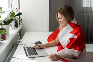 mulher mãos e bandeira do Canadá em computador, computador portátil teclado foto