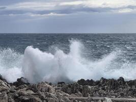 ondas falhando em a pedras às a costa foto