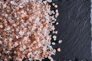 cristais do Rosa comestível himalaia sal em fundo ardósia pedra. foto
