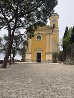 uma amarelo Igreja com uma relógio torre em topo foto