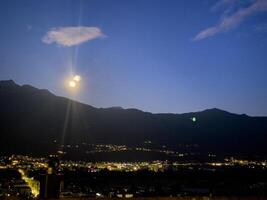 uma cheio lua é visto sobre a montanhas foto