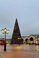 uma Natal árvore dentro uma praça com uma rua luz foto