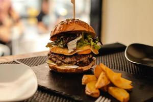 hambúrguer com ovo e batata frita servido em restaurante foto