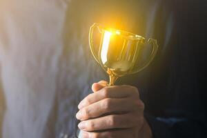 o negócio homem segurando uma troféu a partir de dele sucesso. o negócio recompensa para seu esforço para sucesso dentro seu vida foto