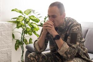 jovem caucasiano homem vestindo camuflar exército uniforme implorando e Rezar com mãos juntos com esperança expressão em face muito emocional e preocupado. implorando. foto